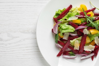 Plate with delicious beet salad on wooden background, top view