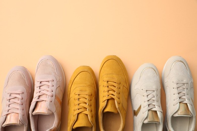 Different stylish shoes on orange background, flat lay. Space for text