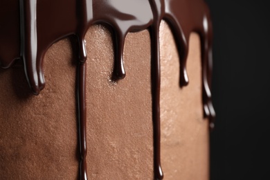 Photo of Freshly made delicious chocolate cake against black background, closeup