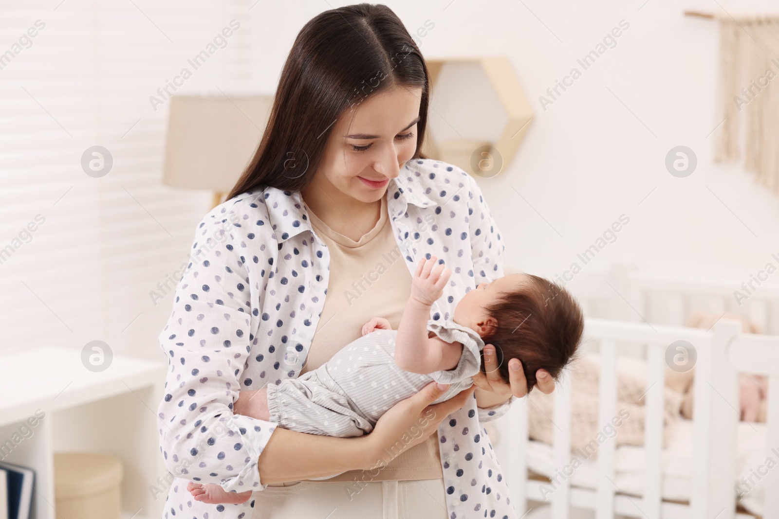 Photo of Mother with her sleeping newborn baby at home