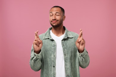 Photo of Young man crossing his fingers on pink background