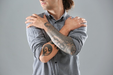 Photo of Young man with stylish tattoos on grey background