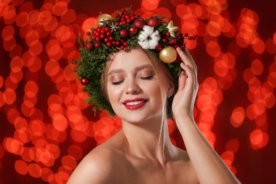 Beautiful young woman wearing Christmas wreath on blurred background. Bokeh effect