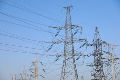 Photo of High voltage towers against blue sky on sunny day