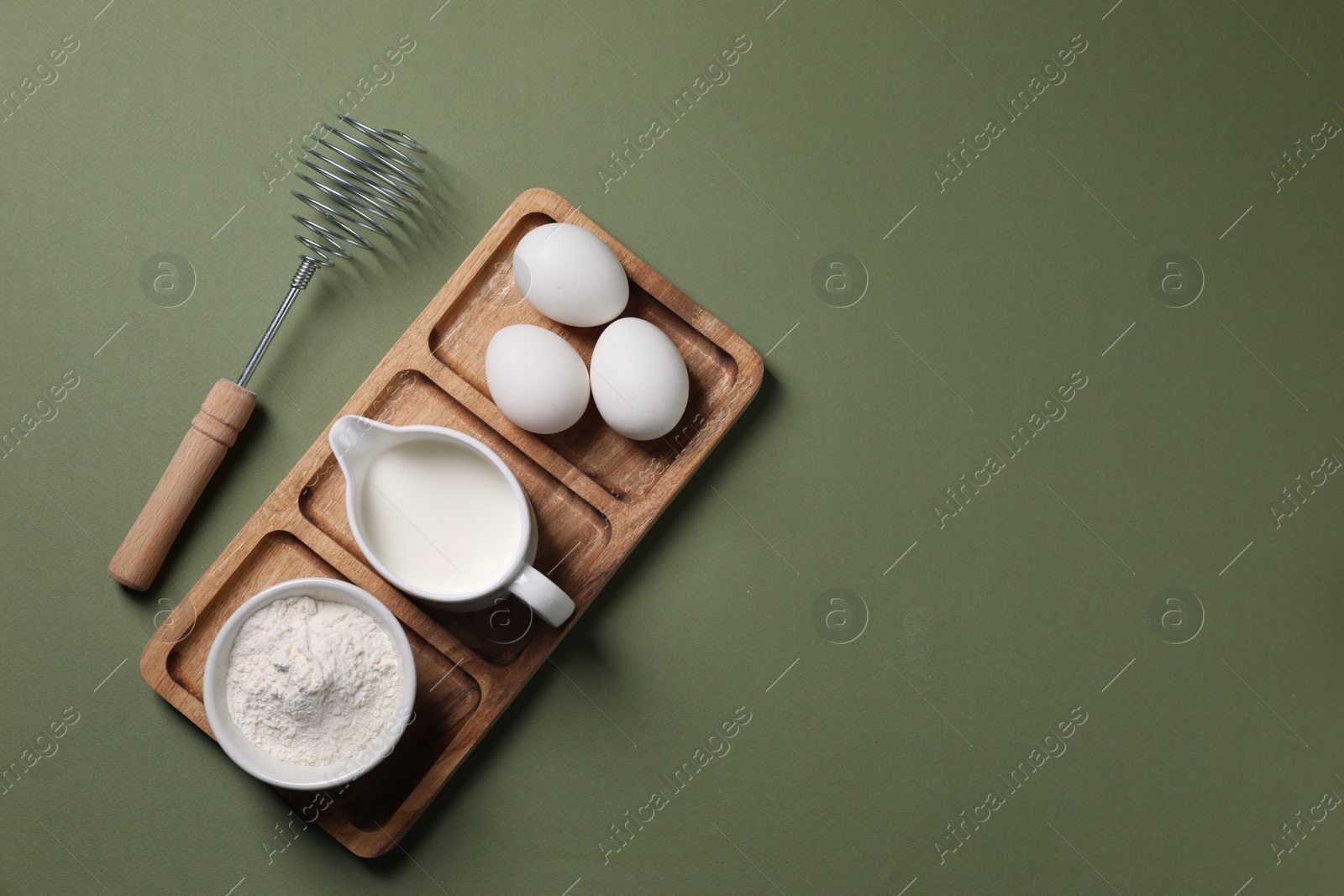 Photo of Metal whisk and dough ingredients on khaki background, flat lay. Space for text