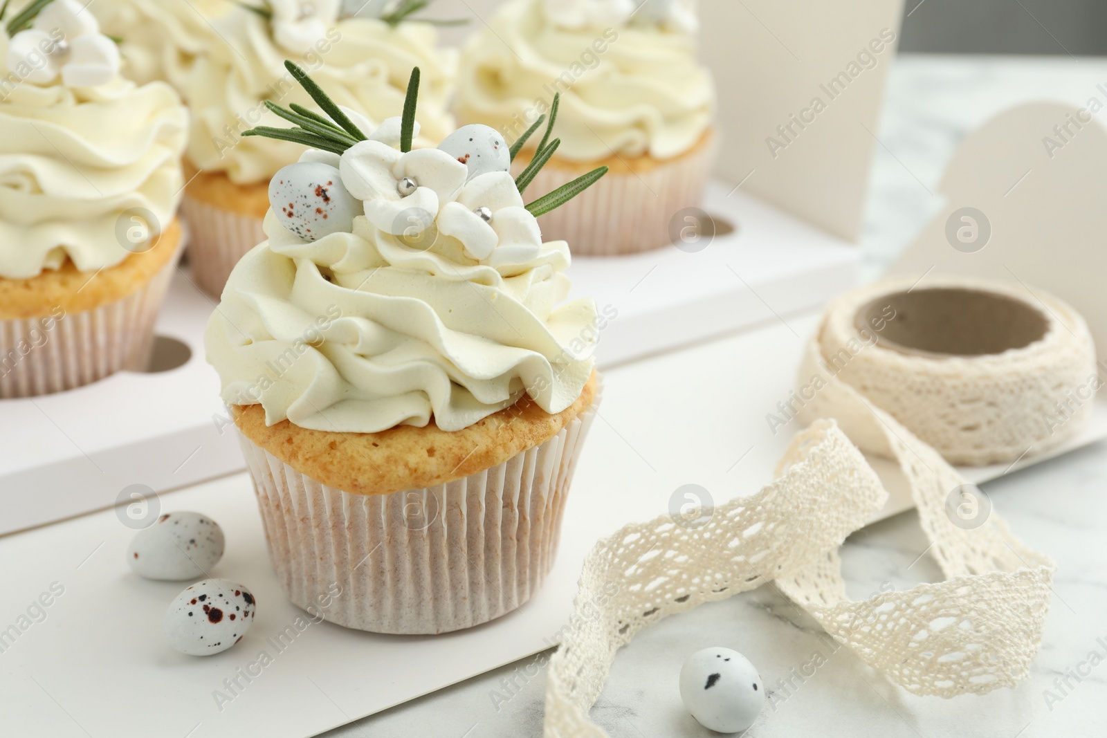 Photo of Tasty Easter cupcakes with vanilla cream on white marble table