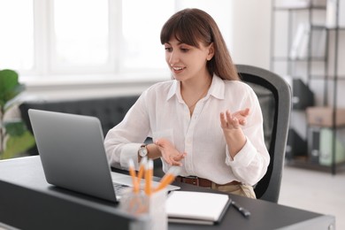 Woman using video chat during webinar at table in office