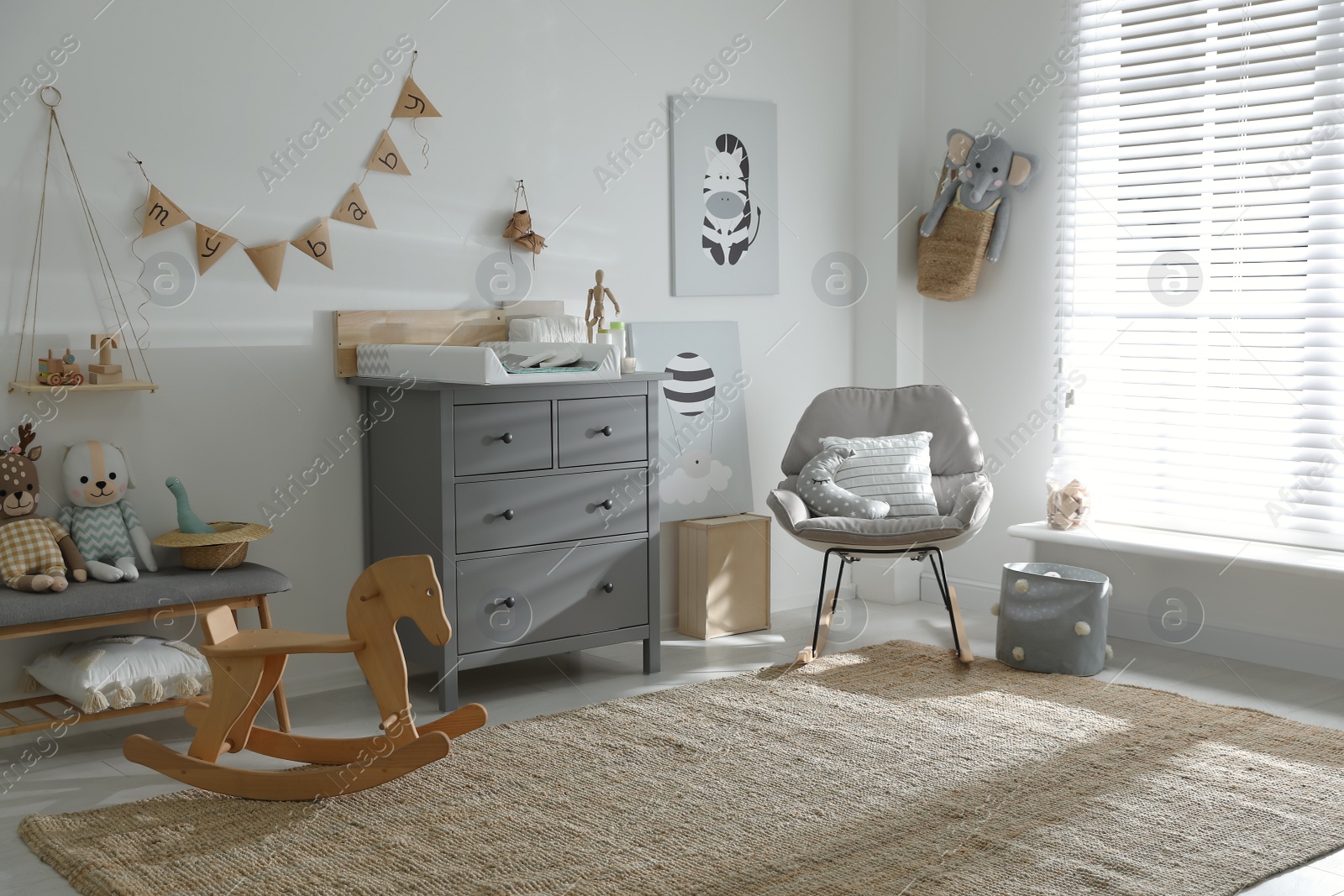 Photo of Beautiful baby room interior with toys, rocking chair and modern changing table