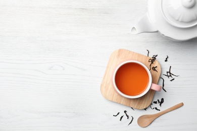 Photo of Cup of black tea on wooden table, top view