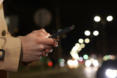 Man using smartphone on night city street, closeup. Space for text