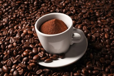 Photo of Cup with ground coffee on roasted beans