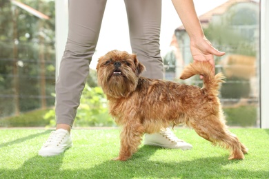 Young woman and cute Brussels Griffon dog indoors. Champion training