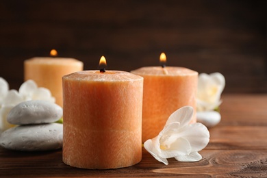 Photo of Burning candles, spa stones and flowers on table. Space for text