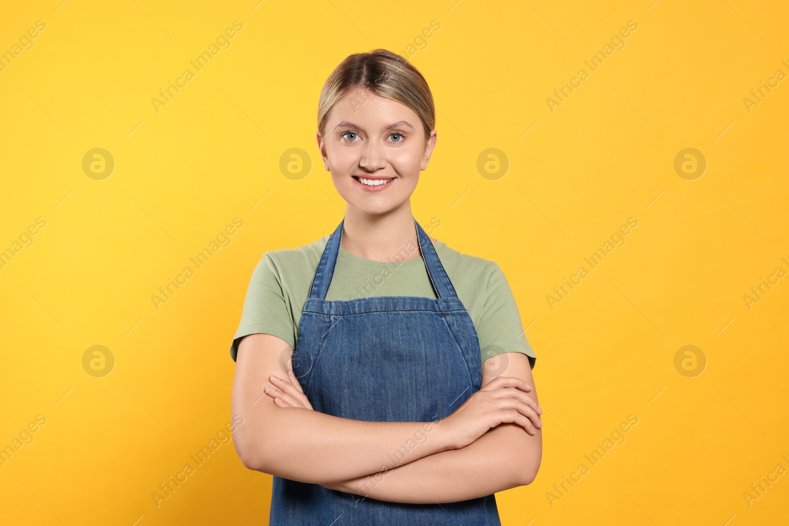 Photo of Beautiful young woman in denim apron on orange background