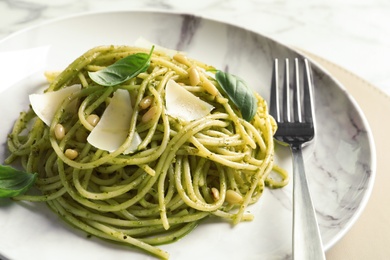 Plate with delicious basil pesto pasta on table, closeup