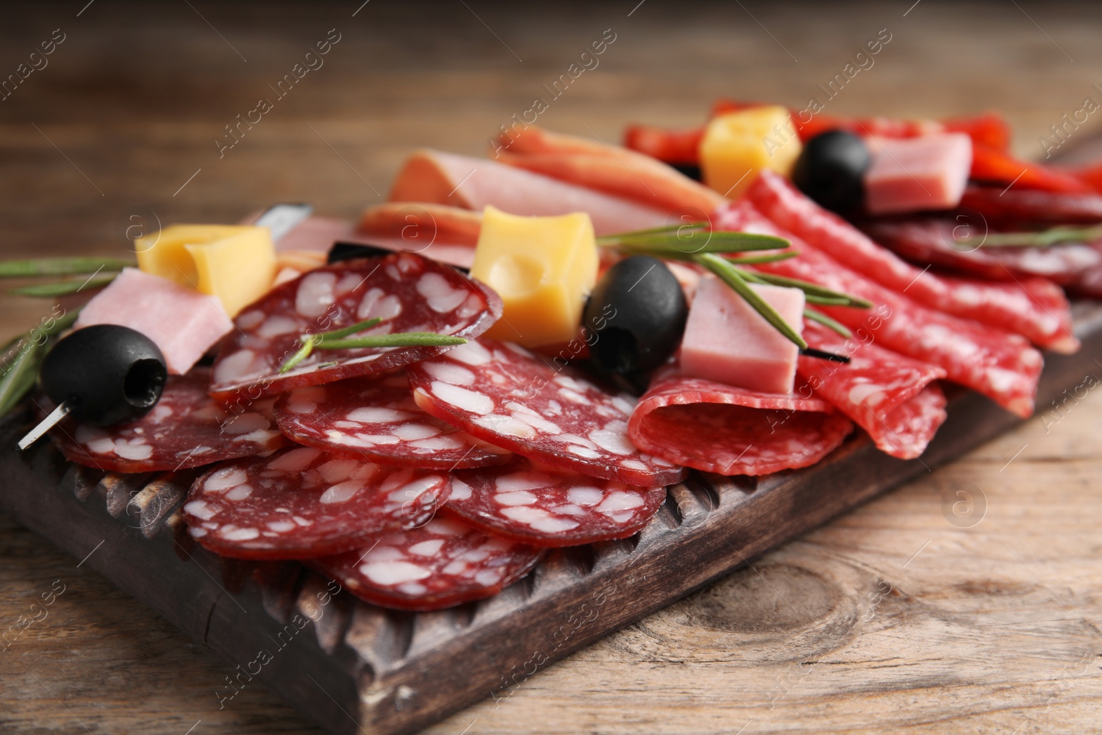 Photo of Tasty ham with other delicacies served on wooden table, closeup