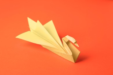 Photo of Origami art. Paper swan on orange background, closeup
