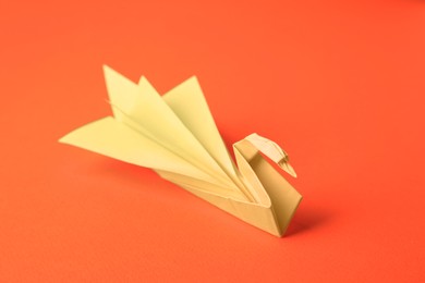 Origami art. Paper swan on orange background, closeup