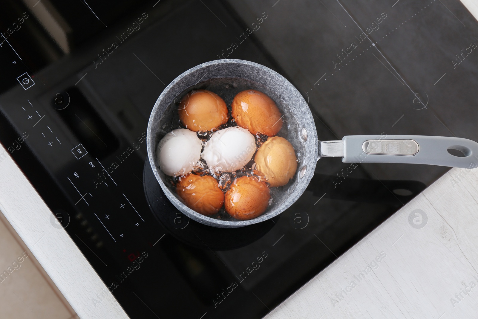 Photo of Chicken eggs boiling in saucepan on electric stove, top view