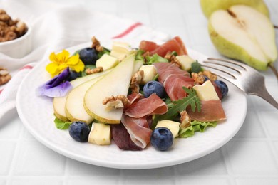 Photo of Tasty salad with brie cheese, prosciutto, walnuts and pear on white tiled table, closeup