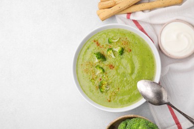 Photo of Delicious broccoli cream soup served on light table, flat lay. Space for text
