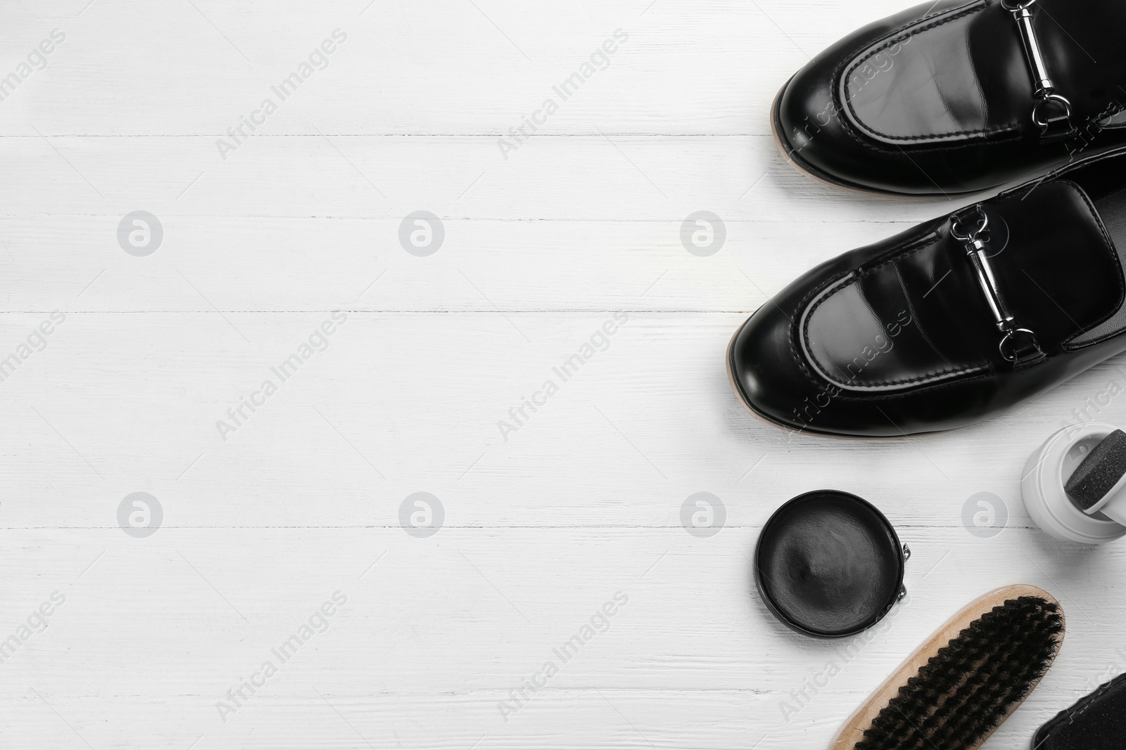 Photo of Flat lay composition with shoe care accessories and footwear on white wooden background. Space for text