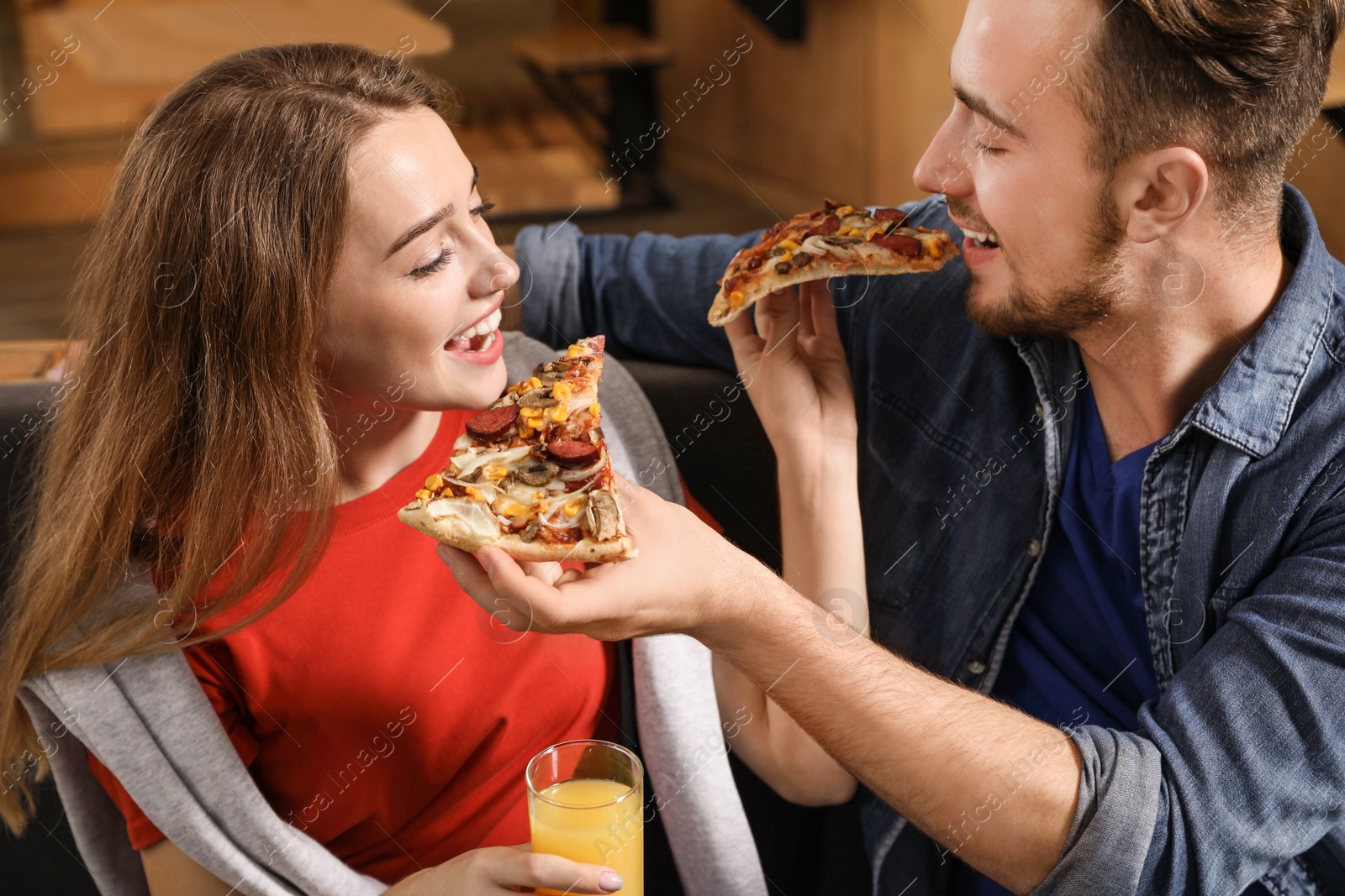 Photo of Young couple eating delicious pizza in cafe