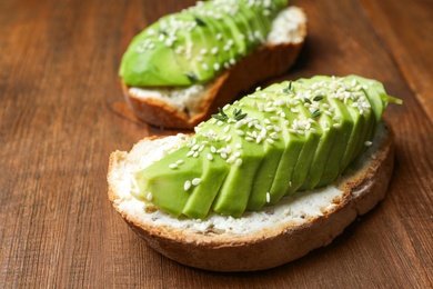 Photo of Tasty sandwich with avocado on wooden table, closeup