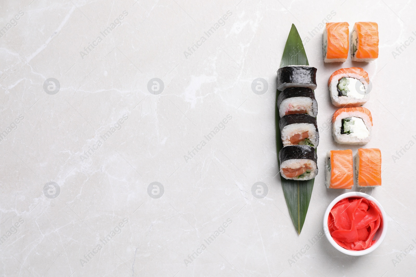 Photo of Different tasty sushi rolls and ginger on grey table, flat lay. Space for text