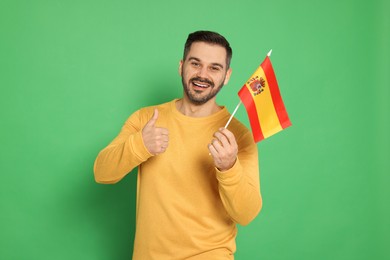 Photo of Man with flag of Spain showing thumb up on green background