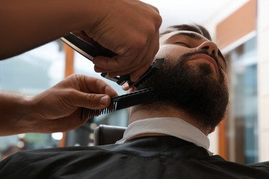 Professional hairdresser working with client in barbershop, closeup