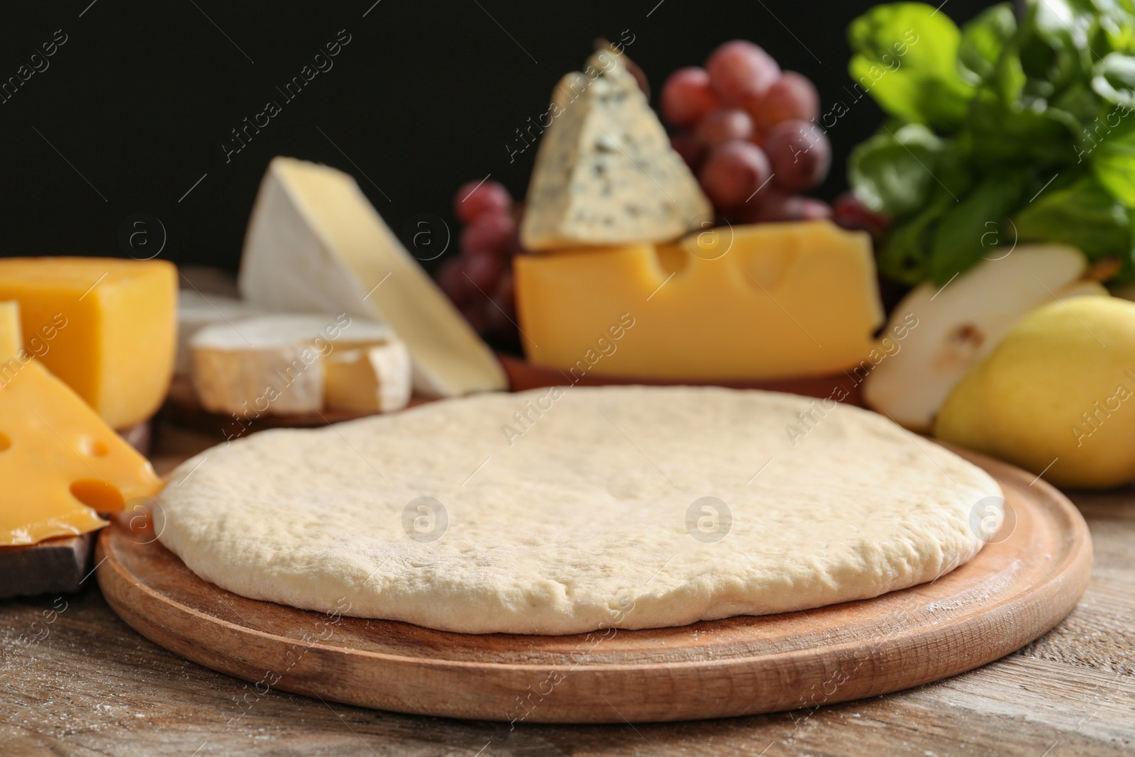 Photo of Pizza crust and fresh ingredients on wooden table, closeup