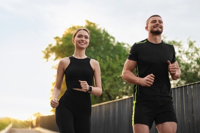 Photo of Attractive sporty couple in fitness clothes jogging outdoors