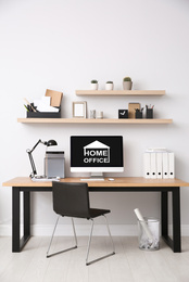 Image of Modern computer with text HOME OFFICE on white wooden indoors 