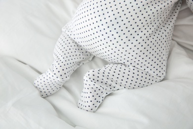 Adorable baby in cute footie on white sheet, closeup