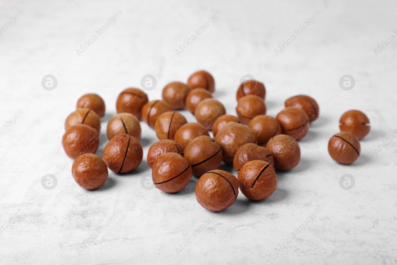 Photo of Delicious organic Macadamia nuts on white textured table