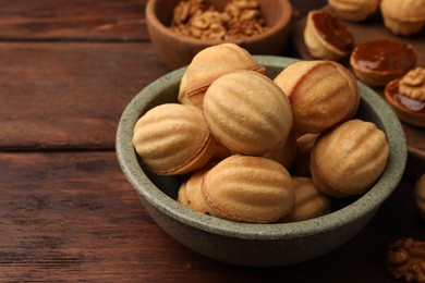 Photo of Delicious nut shaped cookies with boiled condensed milk on wooden table, closeup