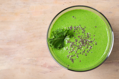 Photo of Tasty kale smoothie with chia seeds on wooden table, top view. Space for text