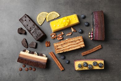 Different delicious cakes and ingredients on grey table, flat lay