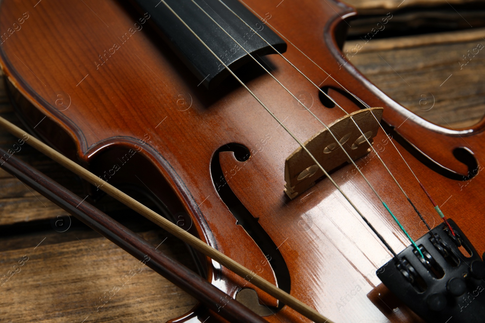 Photo of Classic violin and bow on wooden background, closeup