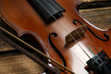 Classic violin and bow on wooden background, closeup