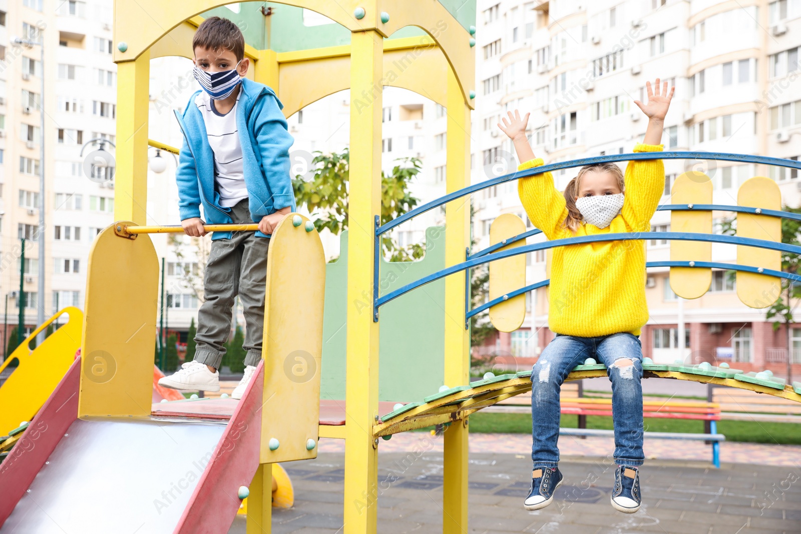 Photo of Little children with medical face masks on playground during covid-19 quarantine