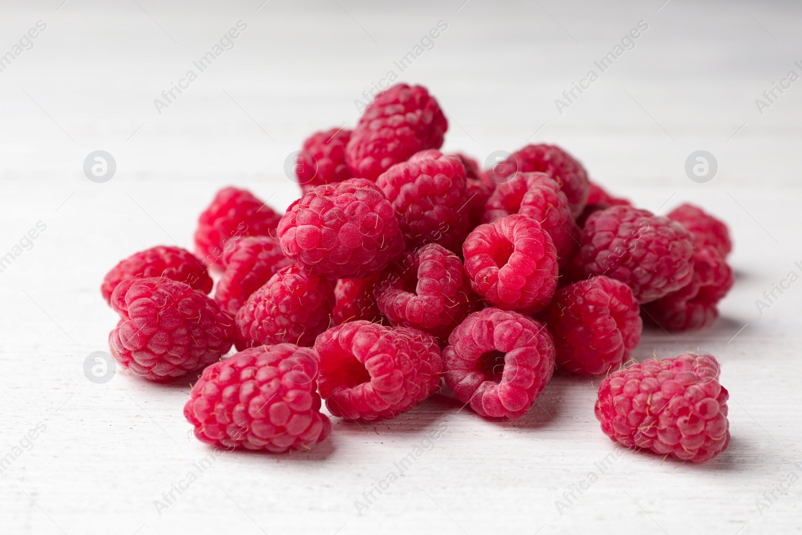 Photo of Delicious fresh ripe raspberries on white wooden table, closeup view