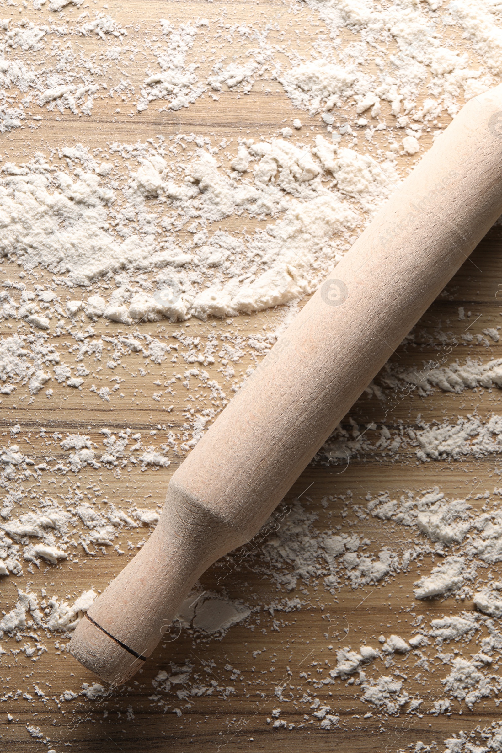 Photo of Scattered flour and rolling pin on wooden table, top view