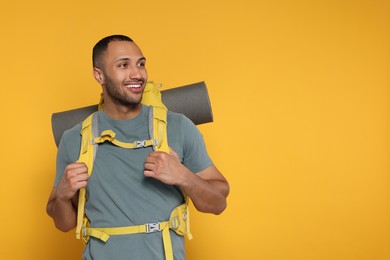 Photo of Happy tourist with backpack on yellow background, space for text