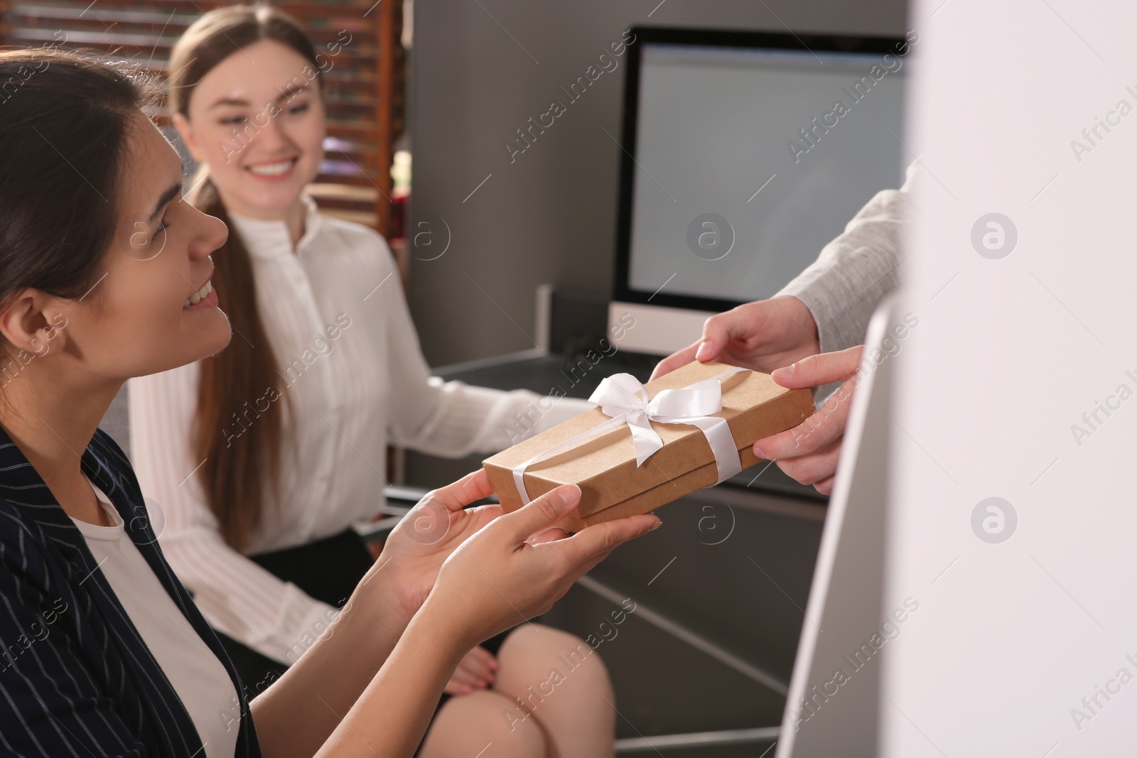 Photo of Man presenting gift to his colleague in office