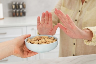 Woman suffering from food allergies refusing offered peanuts by her friend at home, closeup