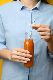 Photo of Woman holding bottle of tasty carrot juice, closeup