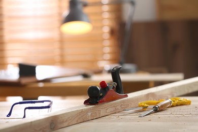 Photo of Different carpenter's tools and wooden bar on table in workshop. Space for text