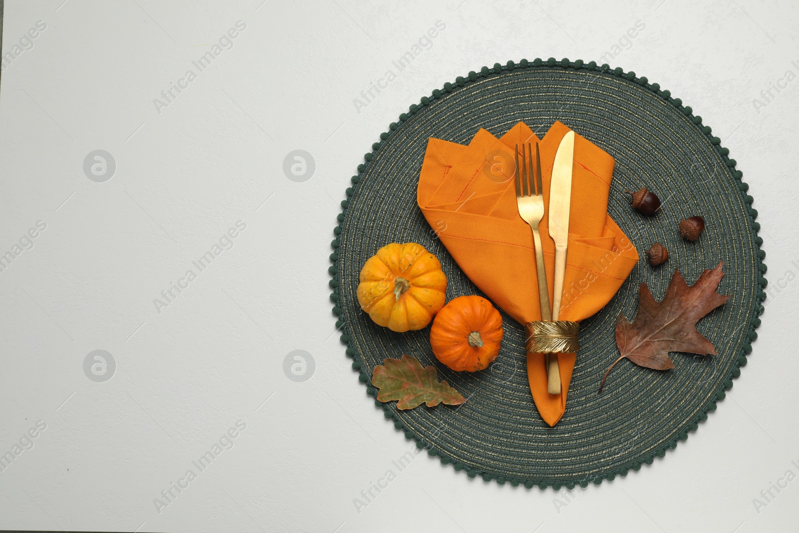 Photo of Cutlery, napkin and autumn decoration on white background, flat lay with space for text. Table setting